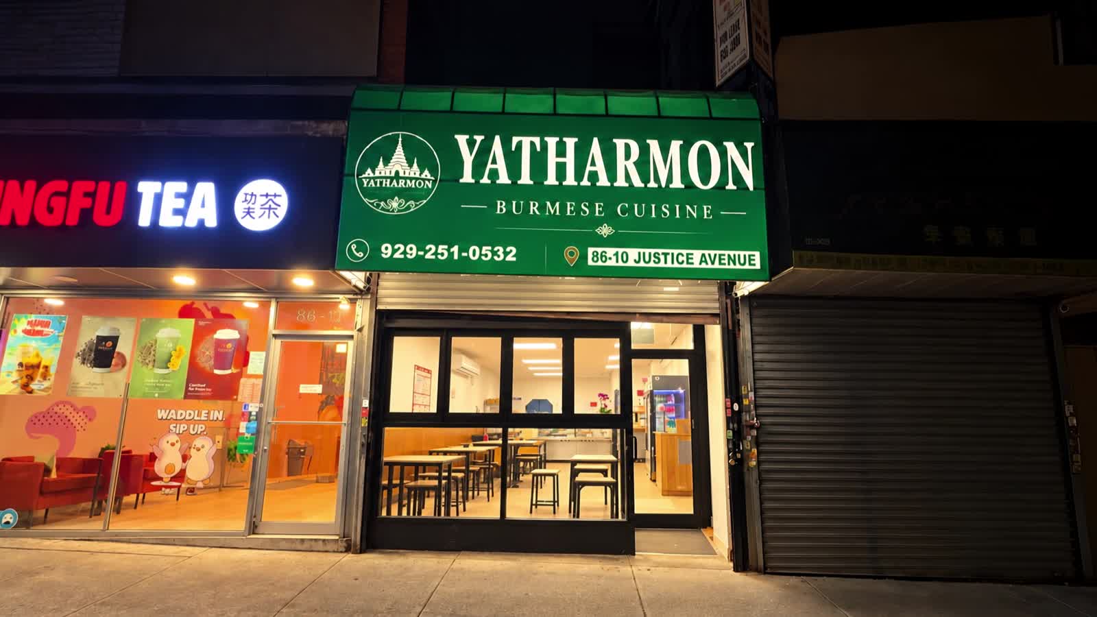 Yatharmon storefront at night, green awning lit above the glass entrance