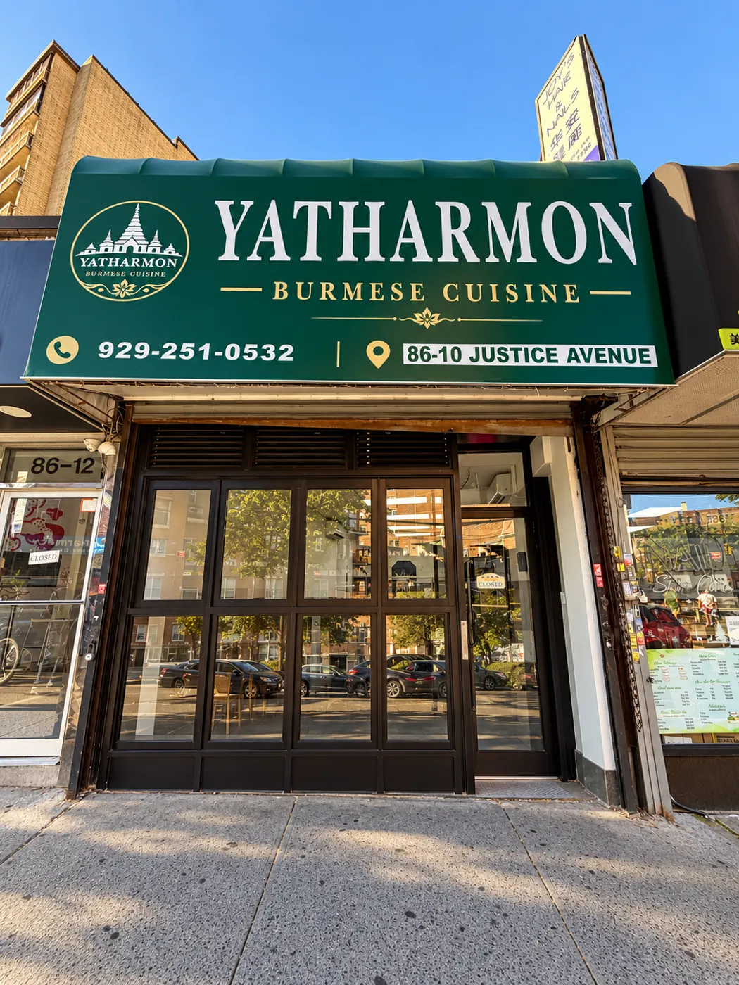 Yatharmon's green awning and glass storefront on Justice Avenue in daylight