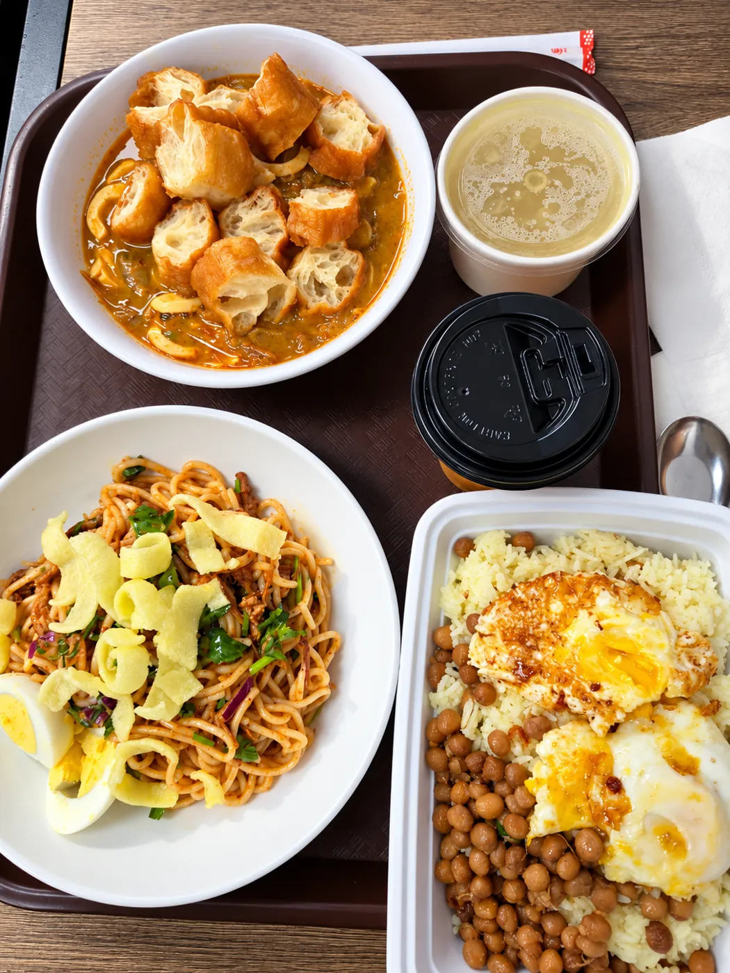 Tray with a bowl of soup with fried bread, noodle salad with egg, rice with chickpeas and fried eggs, and a cup of broth